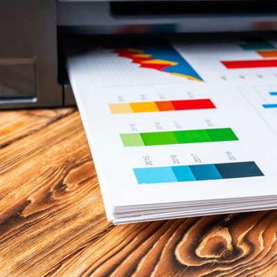 Modern laser printer with paper on wooden background close up